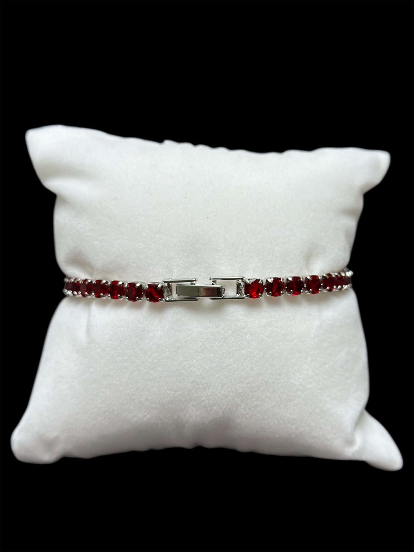 Pulsera tenis roja 3 mm sobre almohadilla blanca, destacando su elegancia y brillo con chapa de oro 14k.