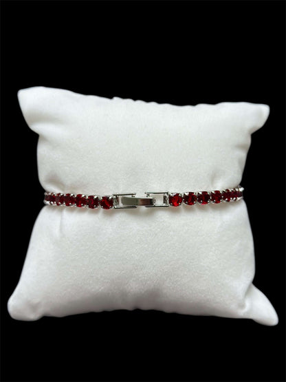 Pulsera tenis roja 3 mm sobre almohadilla blanca, destacando su elegancia y brillo con chapa de oro 14k.